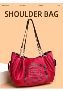 Detail of red velvet tote bag featuring a vintage crown print and metal chain strap