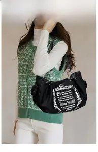 Detail of vintage black canvas tote bag featuring chain straps and retro graphic print