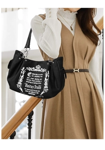 Detail of black canvas tote bag with vintage print and side drawstring on beige outfit