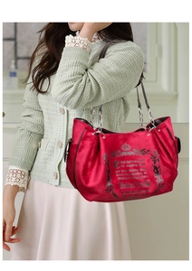 Detail of red velvet tote bag with Gothic crown print and metal chain handle strap