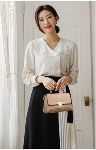 Close-up of beige faux leather handbag with crocodile pattern flap and gold square lock