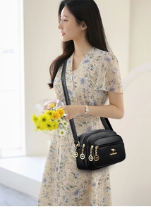 Detail of black pebbled leather crossbody bag with triple zippers and golden kangaroo logo