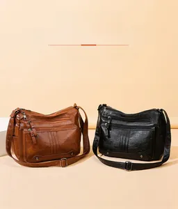 Close-up of brown and black leather bags with multi-zipper pockets and adjustable straps