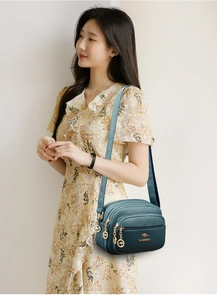 Detail view of dark green textured leather crossbody bag with triple zipper design