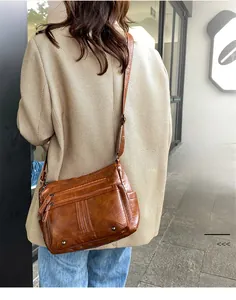 Brown vintage faux leather crossbody bag with multi-pocket design shown on model's shoulder
