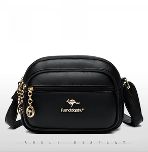 Detail of black textured leather crossbody bag with double gold zippers and kangaroo logo