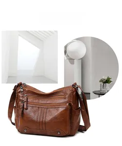 Detail view of brown PU leather crossbody bag with multiple zip pockets and silver zippers