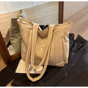 Detail of beige textured tote bag showing thick handles and rope pull zipper pocket