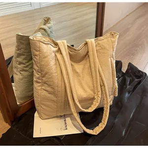 Detail of beige quilted tote bag showing puffer texture and sturdy wide shoulder strap