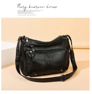 Detail of black soft leather crossbody bag showing dual zipper pockets and rivet accents