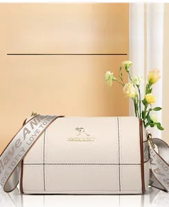 Détail du sac cylindrique beige avec texture grainée et large bandoulière en jacquard
