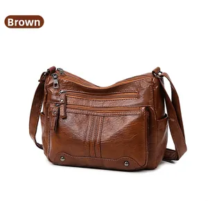 Detail of brown soft PU leather crossbody bag with multiple front zipper pockets