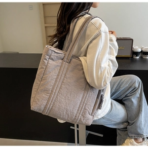 Detail of the gray quilted tote bag showing padded fabric texture and shoulder strap