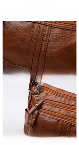 Detail of brown litchi pattern leather bag with multi-layer zippers and neat stitching