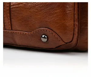 Macro detail of brown litchi leather bag featuring metallic rivets and dual stitching