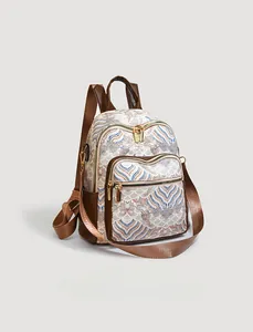 Detailed view of Chinese wave pattern on backpack with brown leather trim and gold zippers