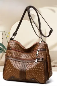 Detail of dark brown woven textured crossbody bag with multiple zipper pockets and rivets