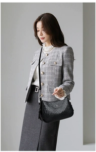 Dettaglio borsa a tracolla nera intrecciata con logo a canguro su abito in tweed grigio