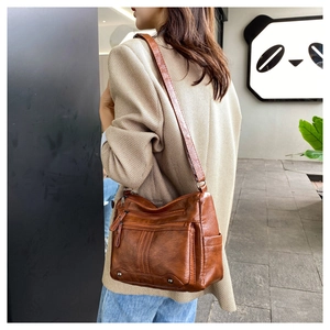 Close-up of brown PU leather bag with multi-layer zipper pockets and metallic rivets