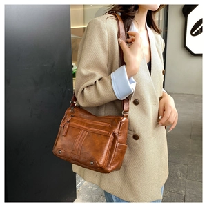 Detail of caramel brown leather shoulder bag with multi-layer zipper pockets for women