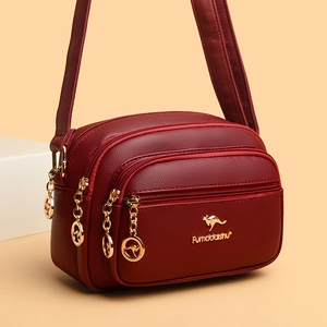 Red pebbled leather crossbody bag with multiple zippers and golden kangaroo emblem