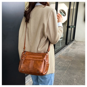 Brown vintage faux leather crossbody bag with multiple zipper pockets on female model