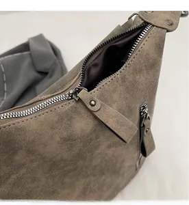 Macro shot of the smooth metal zipper and leather puller on a taupe tote bag detail