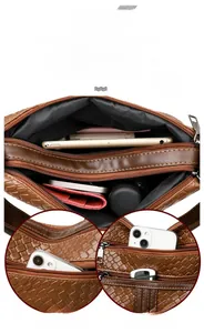 Detail of woven brown leather crossbody bag with multiple zip pockets and large capacity