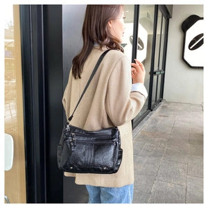 Detail of a black multi-zippered crossbody bag in soft leather on a female model