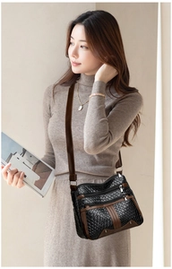 Detail of woven texture and multiple silver zipper pockets on a brown and black crossbody bag