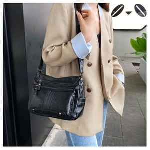 Detail of black multi-zipper crossbody bag with textured leather and silver rivet accents