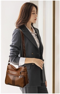 Detail view of a brown woven soft leather shoulder bag with multiple zipper compartments
