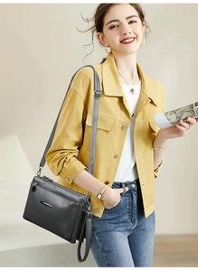 Detail of dark grey multi-layer crossbody bag with adjustable strap and zip compartments