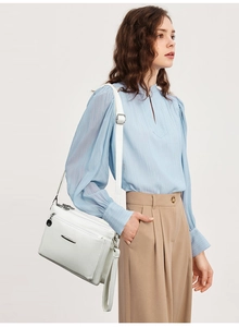 Side view of white faux leather crossbody bag with multiple layers and silver hardware