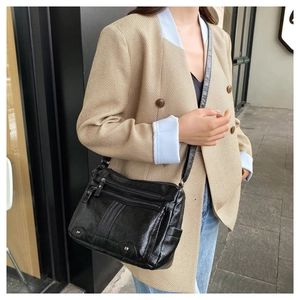 Detail of black soft leather crossbody bag with multiple zippers and metallic studs