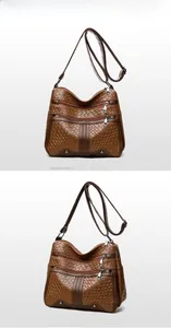 Detail of brown woven faux leather crossbody bag with multiple zipper layers and studs