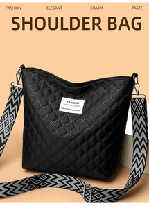 Close-up of quilted shoulder bag with geometric pattern wide strap and logo patch