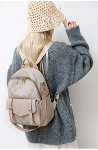 Detail eines beigen gesteppten Nylonrucksacks mit goldenen Beschlägen an einem Model getragen