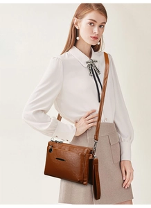 Detail of caramel brown leather crossbody bag with multiple layers and adjustable strap