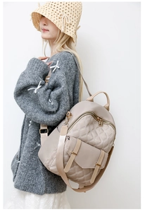 Detail des beigen gesteppten Rucksacks mit Karomuster und goldenem Reißverschluss