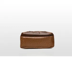 Detailed bottom view of woven brown leather bag with reinforced piping and metal rivets