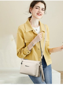 Minimalist beige leather shoulder bag with zipper detail worn with a yellow jacket