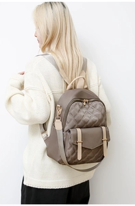 Seitenansicht des taupefarbenen gesteppten Nylon-Rucksacks mit goldener Hardware