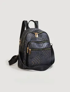 Detail view of black leather backpack with golden wave patterns and three zipper layers