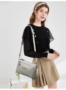 Detail view of stylish grey multi-zipper leather crossbody bag on female model