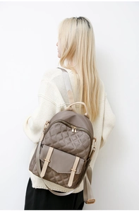 Detail eines khakifarbenen Nylon-Rucksacks mit Steppmuster und Schultergurt an einem Modell