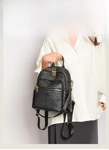 Detail view of black faux leather backpack with golden oriental wave pattern and gold zippers
