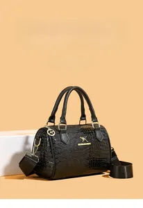Détail du sac cylindre noir texture crocodile avec garniture dorée et bandoulière