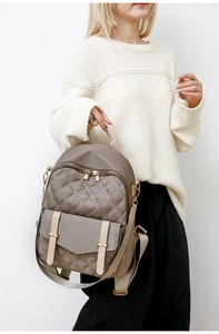 Detail eines beigen gesteppten Nylon-Rucksacks mit goldener Hardware und Vordertasche