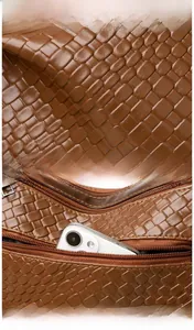 Detail of brown woven leather shoulder bag showing back zipper pocket for phone